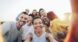 A diverse group of friends taking a joyful selfie outdoors during sunset.